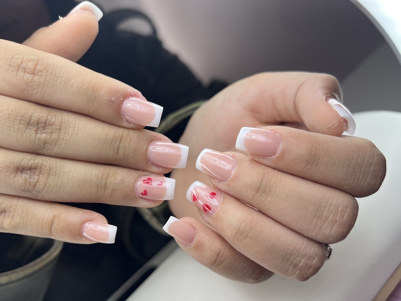 Vierkante French nagels met een klein rood bloemetje als accent