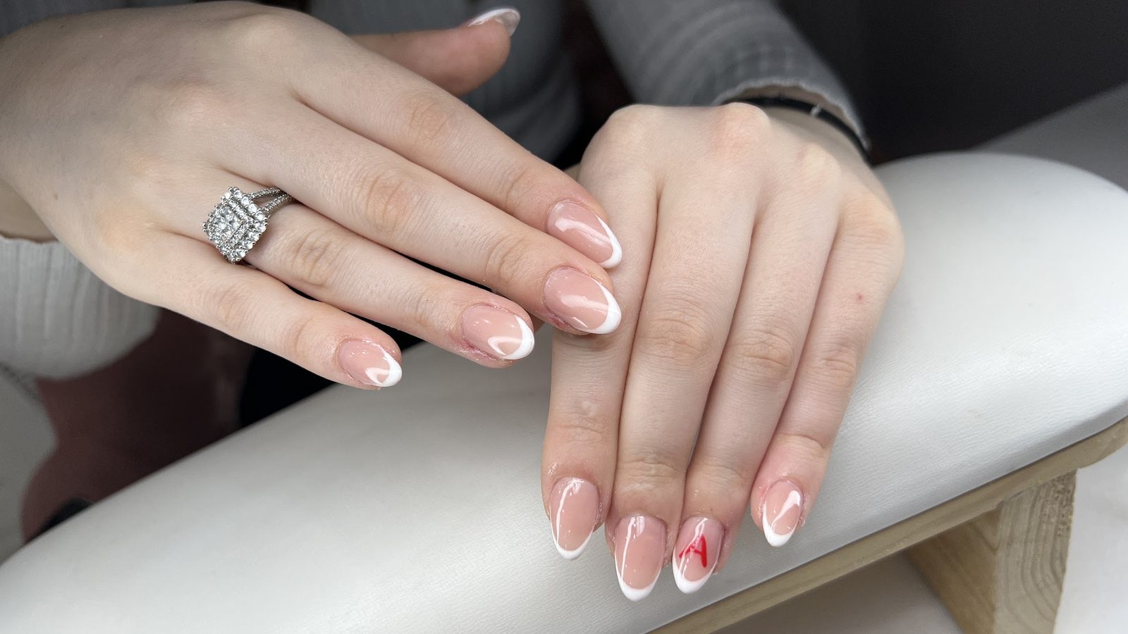 Naturel French manicure met een klein rood accent op de ringvinger