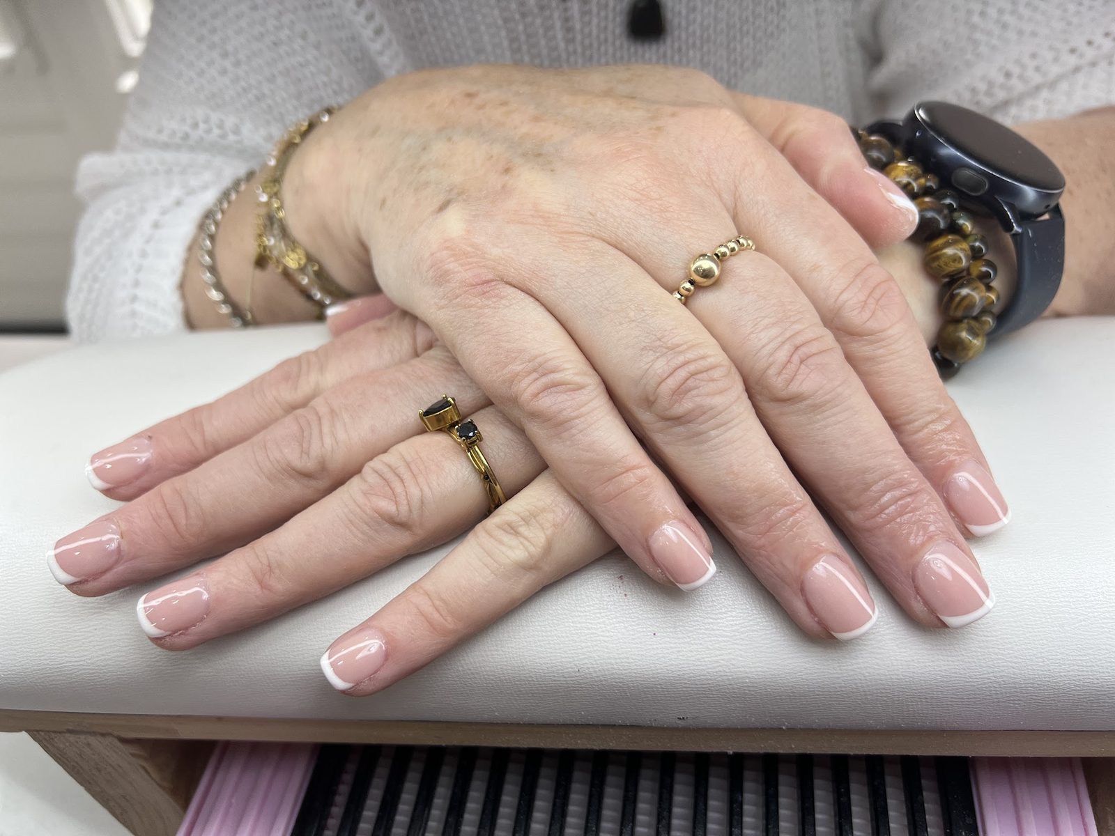 Handen met een frisse French manicure op het witte armsteunkussen in de salon